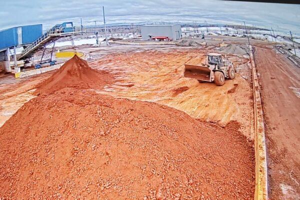 Heavy-duty loader moving refinery sludge pile at aluminium plant